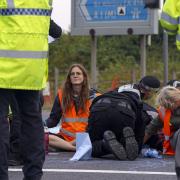 Police work to free protesters who had glued themselves to a slip road of the A1(M)