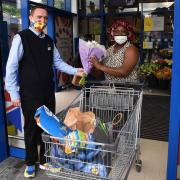 Store manager Chris Pawson presents a bouquet of flowers to the first customer through the door Olukemi Adebayo.