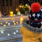 A child adds a candle to the tribute on the steps of the Barking town hall.